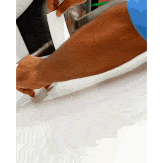 Hand guiding a white sheet of laundry detergent material through the production machine